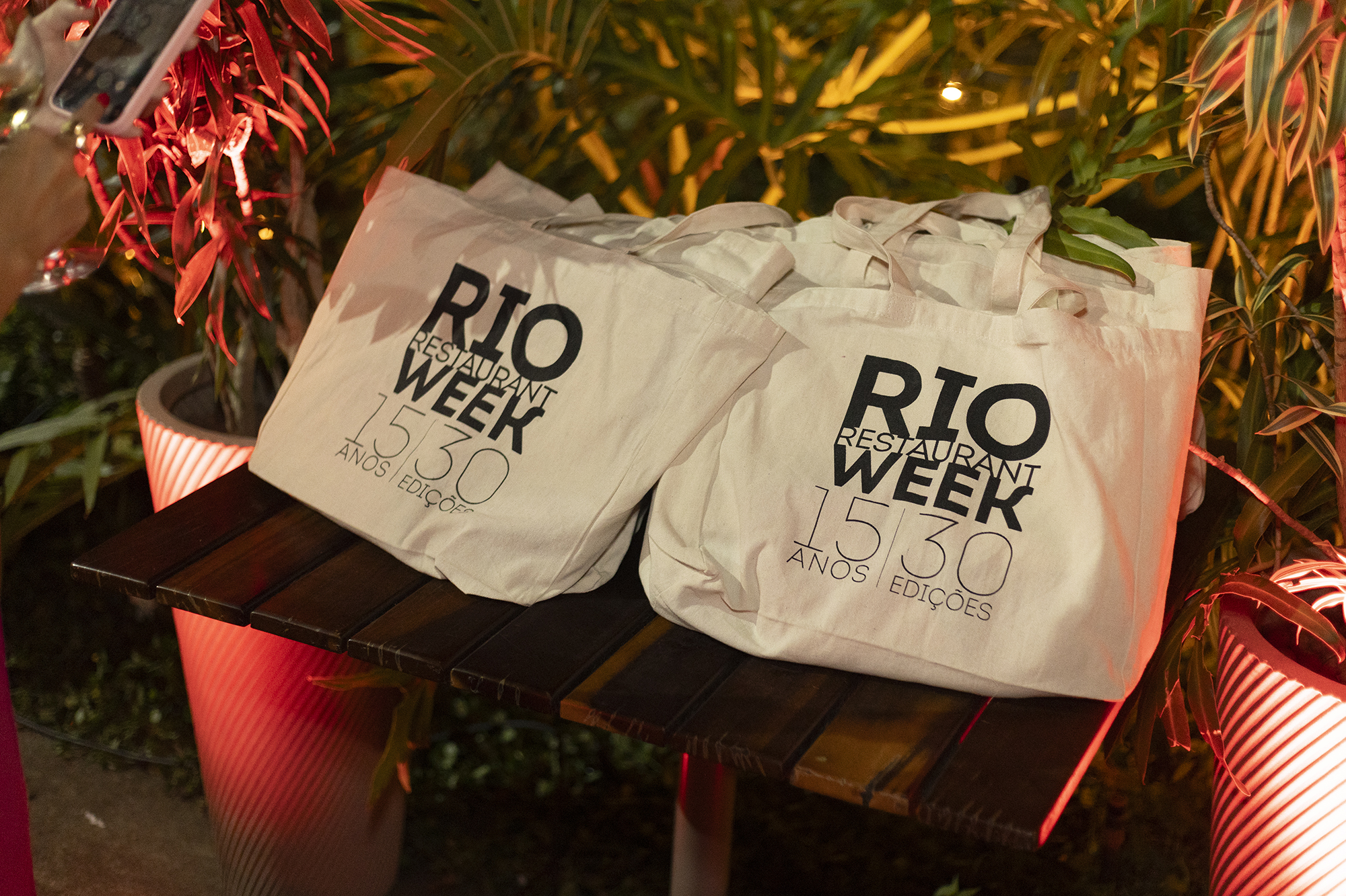 Sacolas ecobags brancas do Rio Restaurant Week 15 anos 30 edições sobre mesa com decoração festiva